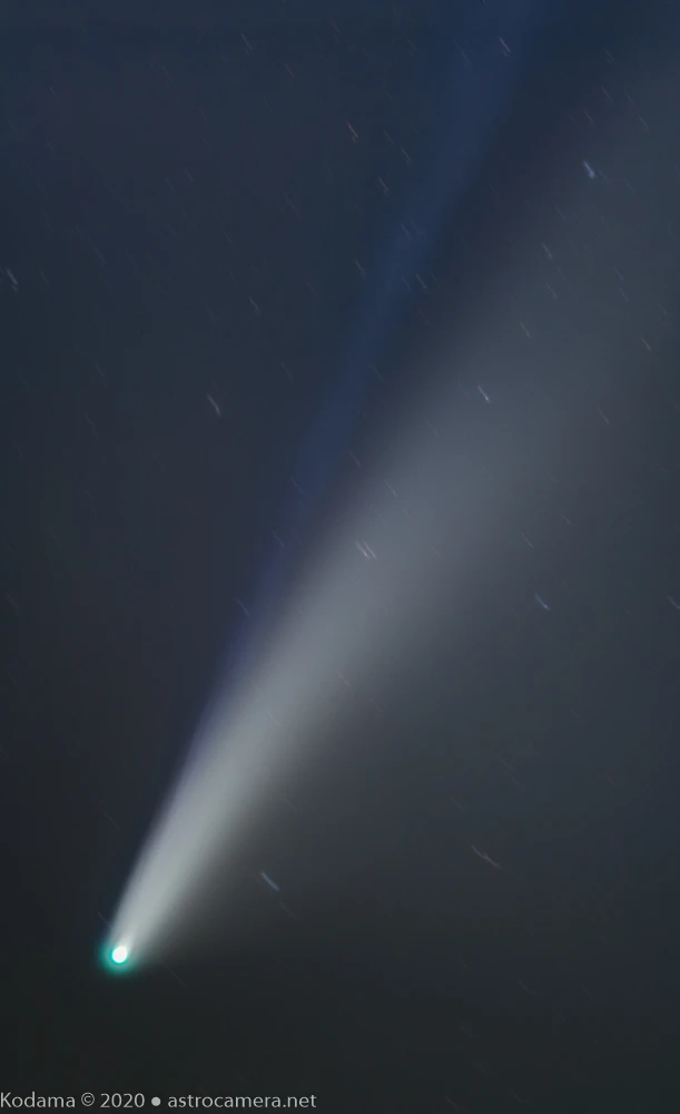 Bright comet with luminous tail streaking diagonally across dark starry night sky.