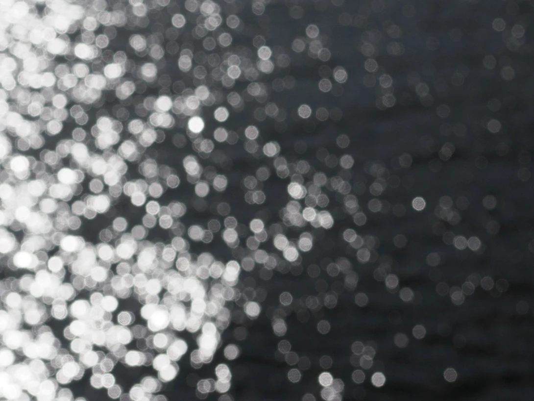Bokeh lights transitioning from bright white orbs on the left to darker tones on the right against a dark background.