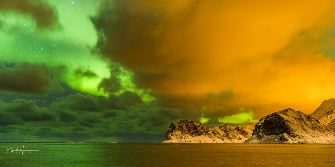 Two opposites at Lofoten in Norway. The green light of the aurora and the yellow light of light pollution.