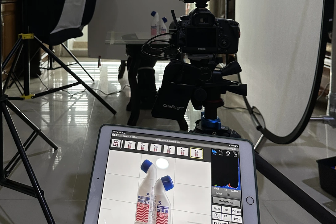 Professional product photography setup with monitor displaying two beverage bottles during live tethering session.