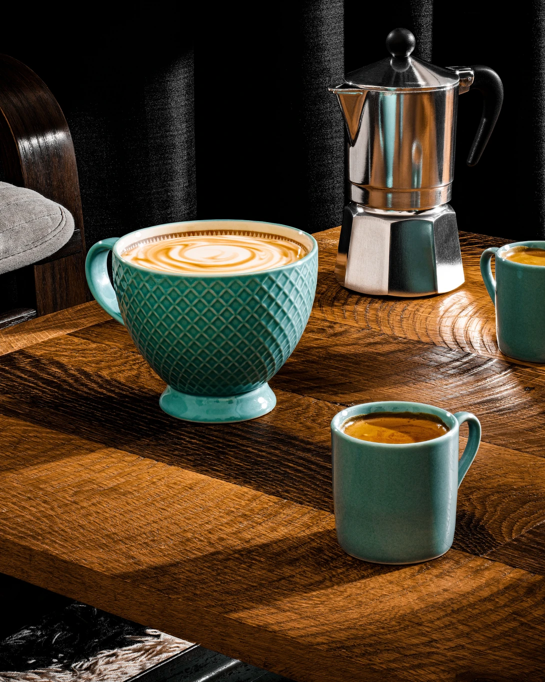 Styled coffee setup with turquoise textured cup and moka pot on wooden surface