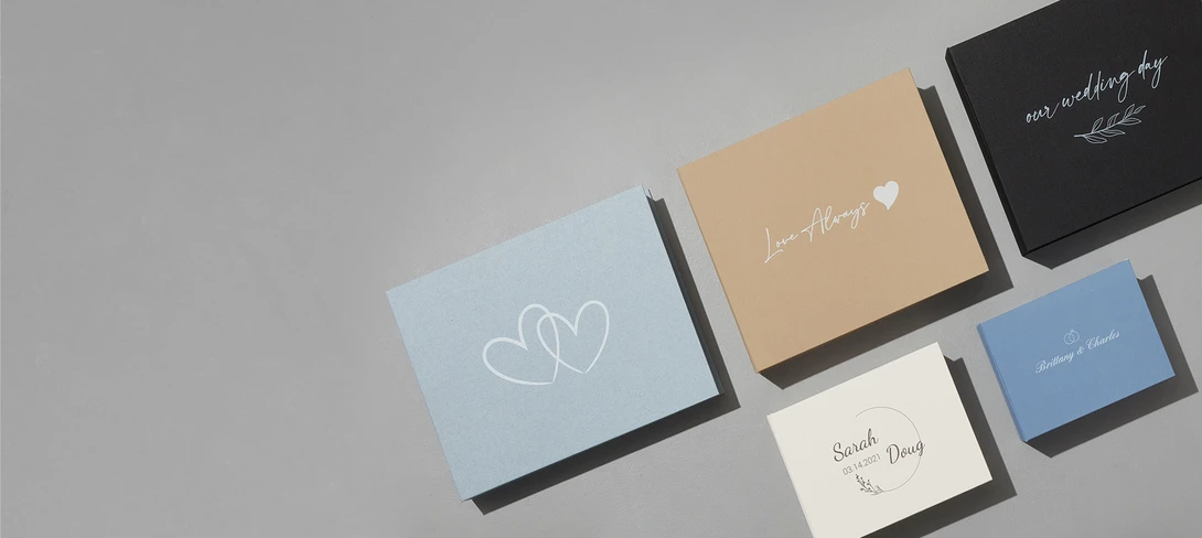 Collection of wedding stationery cards in various colors and sizes arranged on a gray surface.