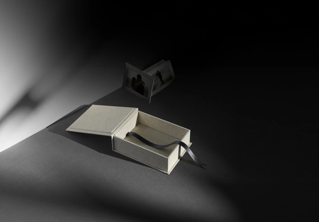 Open book with pages casting sharp shadows under directional studio lighting alongside a dark geometric object.