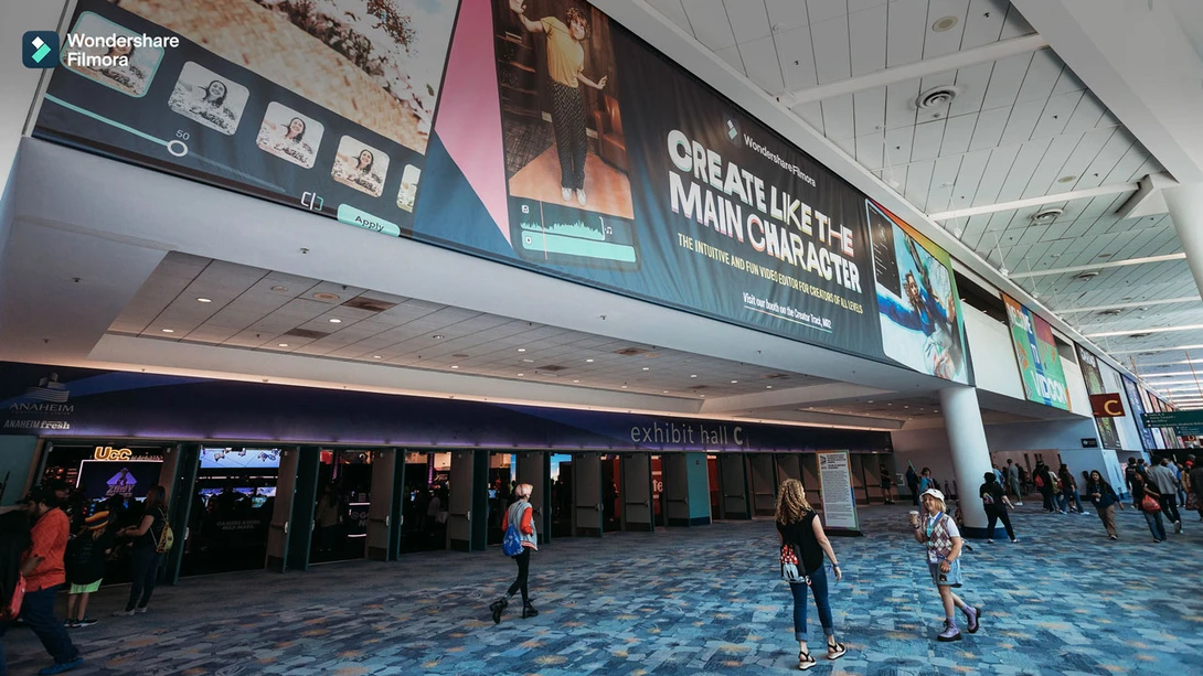 Modern airport terminal with blue patterned flooring, overhead signage, and scattered travelers walking beneath recessed ceiling lights.