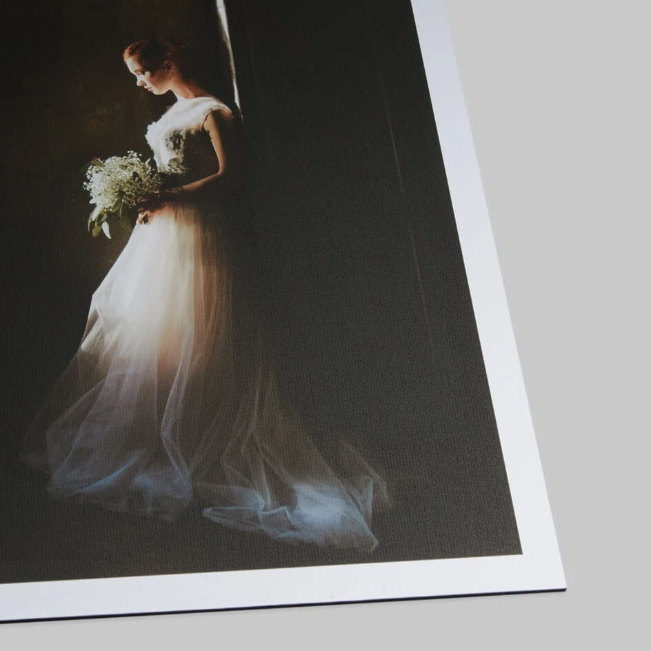 Printed wedding photograph showing bride in flowing tulle gown holding bouquet against dark background.