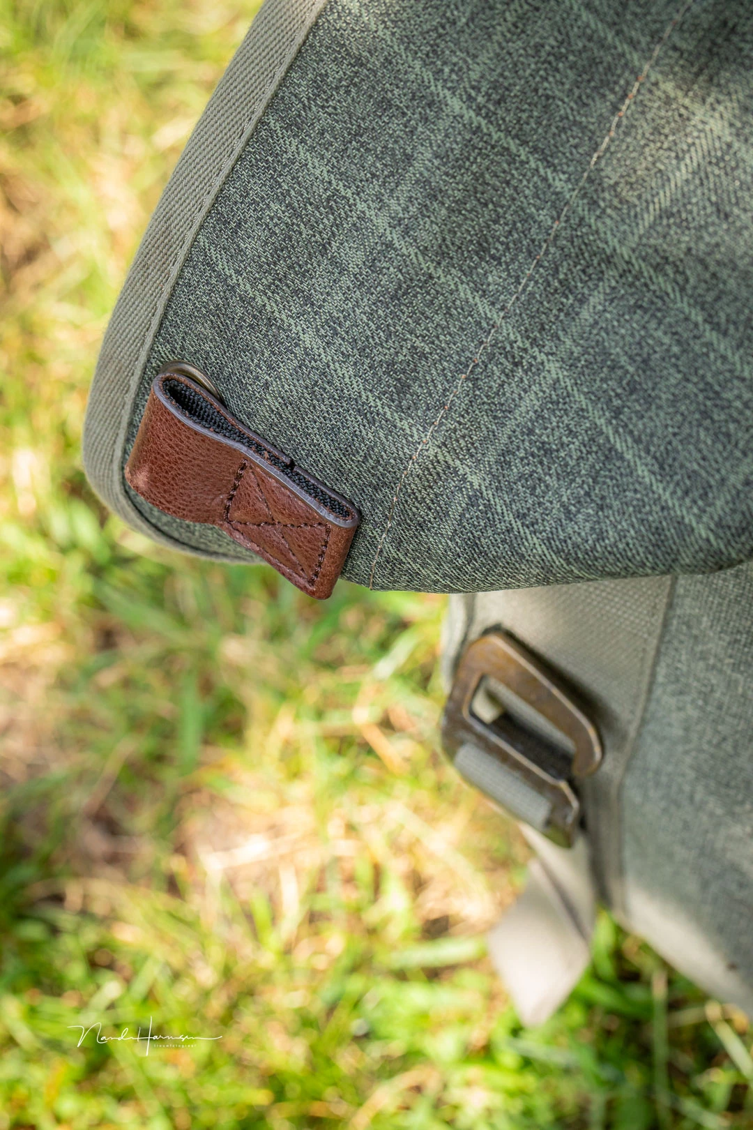 The front pouch cover closes with brass hooks that fit inside these leather loops.