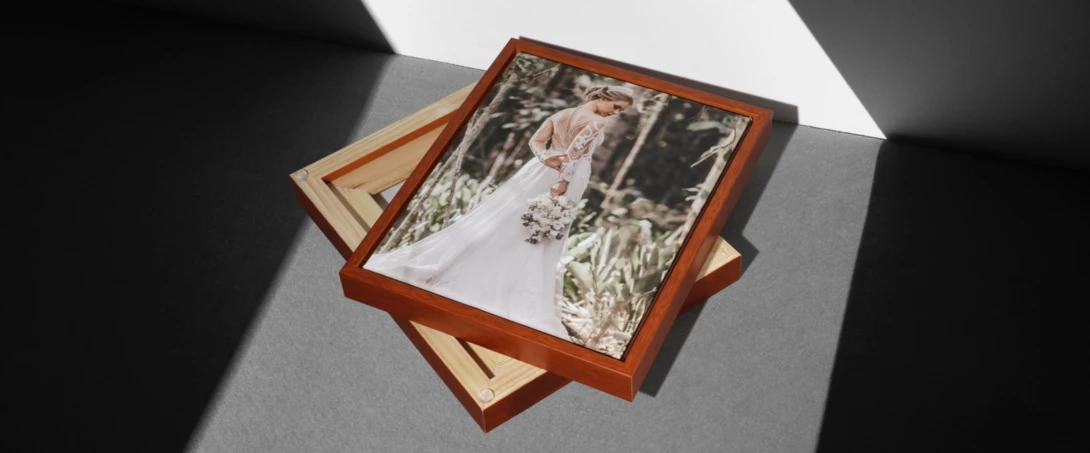 Wooden presentation boxes with a wedding portrait photograph displayed on top in bright sunlight.