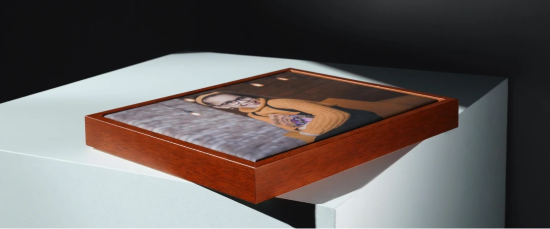 Wooden-framed photo display box with portrait print mounted on white pedestal against dark background.
