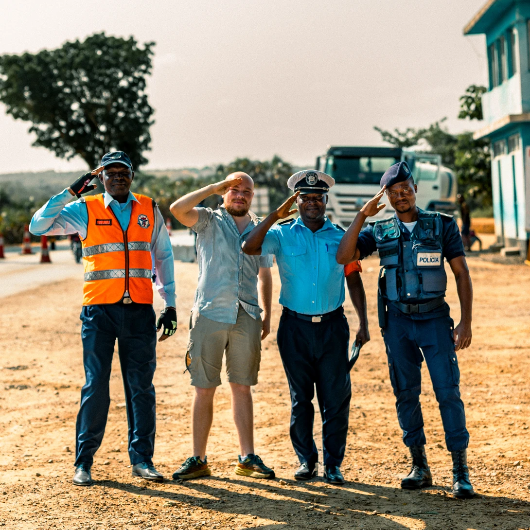 Four people in safety vests and work uniforms stand together on a dusty construction site road.