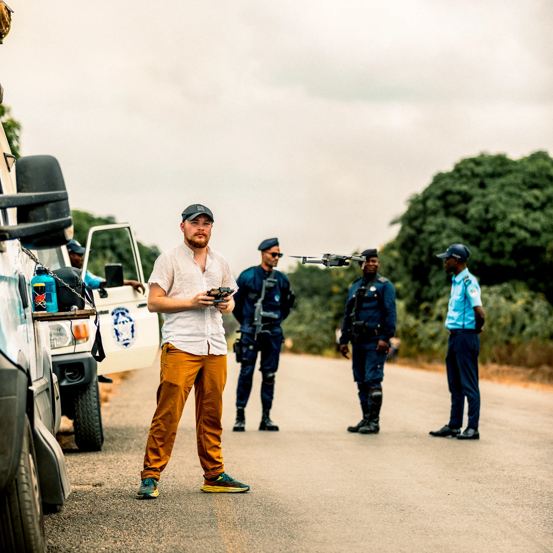 Instructor demonstrating technique to group of students standing on rural road with utility vehicle nearby.