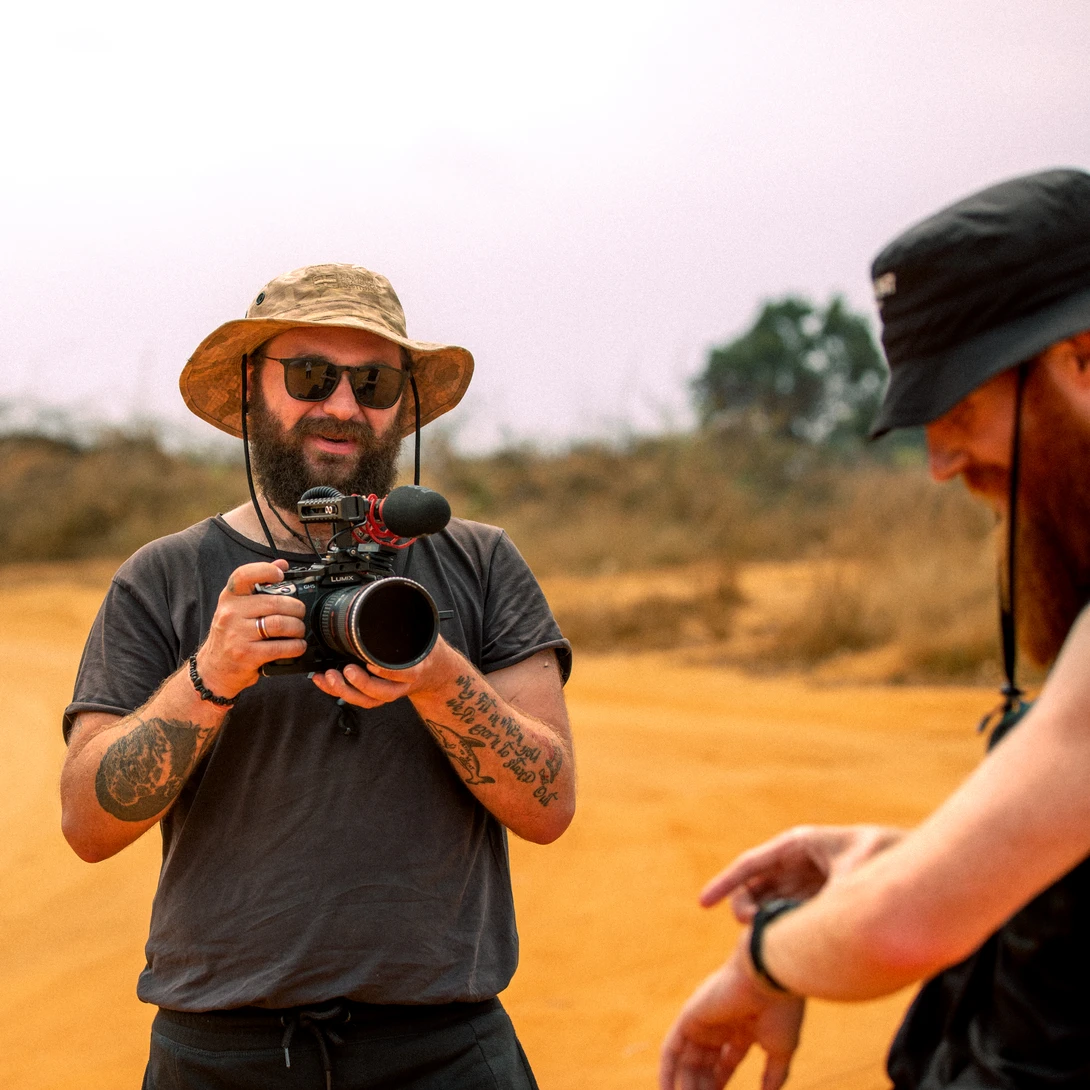 Photographer with camera and telephoto lens in desert landscape during golden hour.
