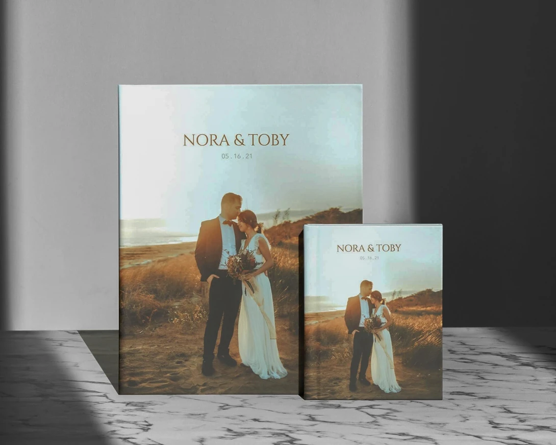 Wedding photo albums displayed in different sizes, featuring a couple in a field at golden hour.