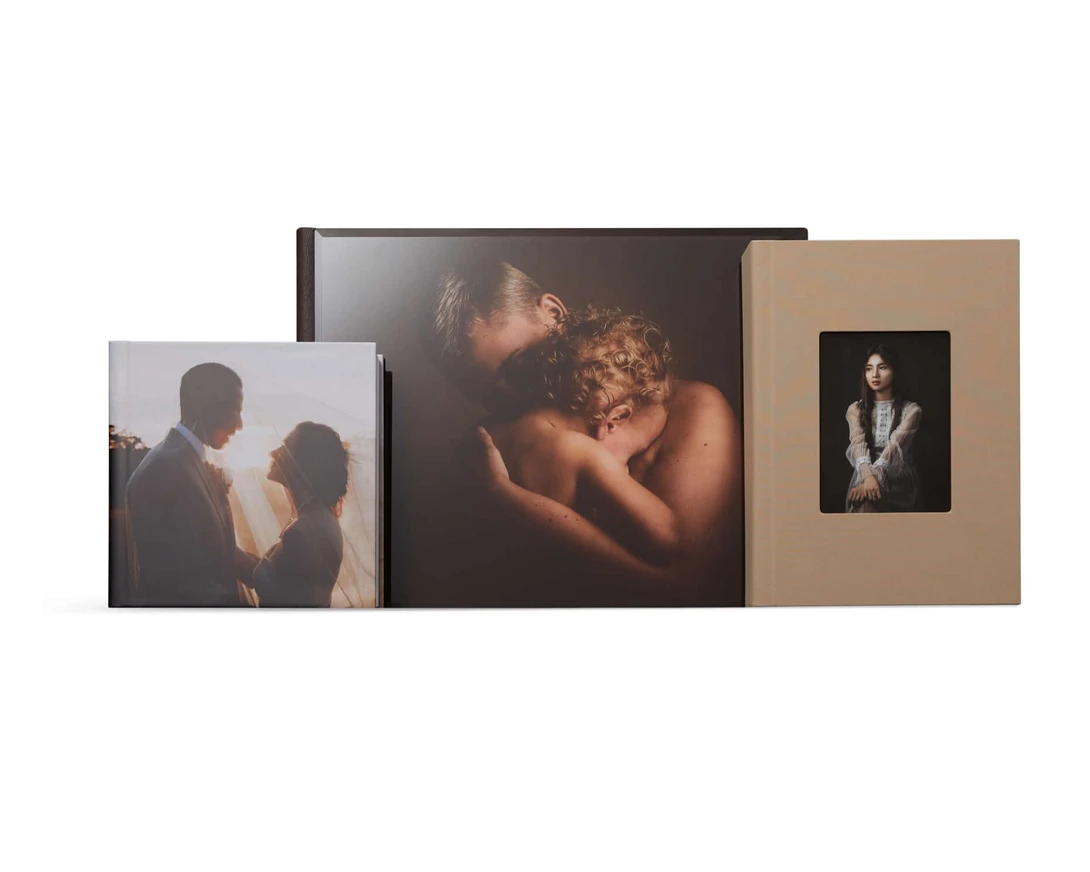 Three professional photo prints and albums displayed in a row, featuring intimate portrait photography with warm, golden-hour lighting.