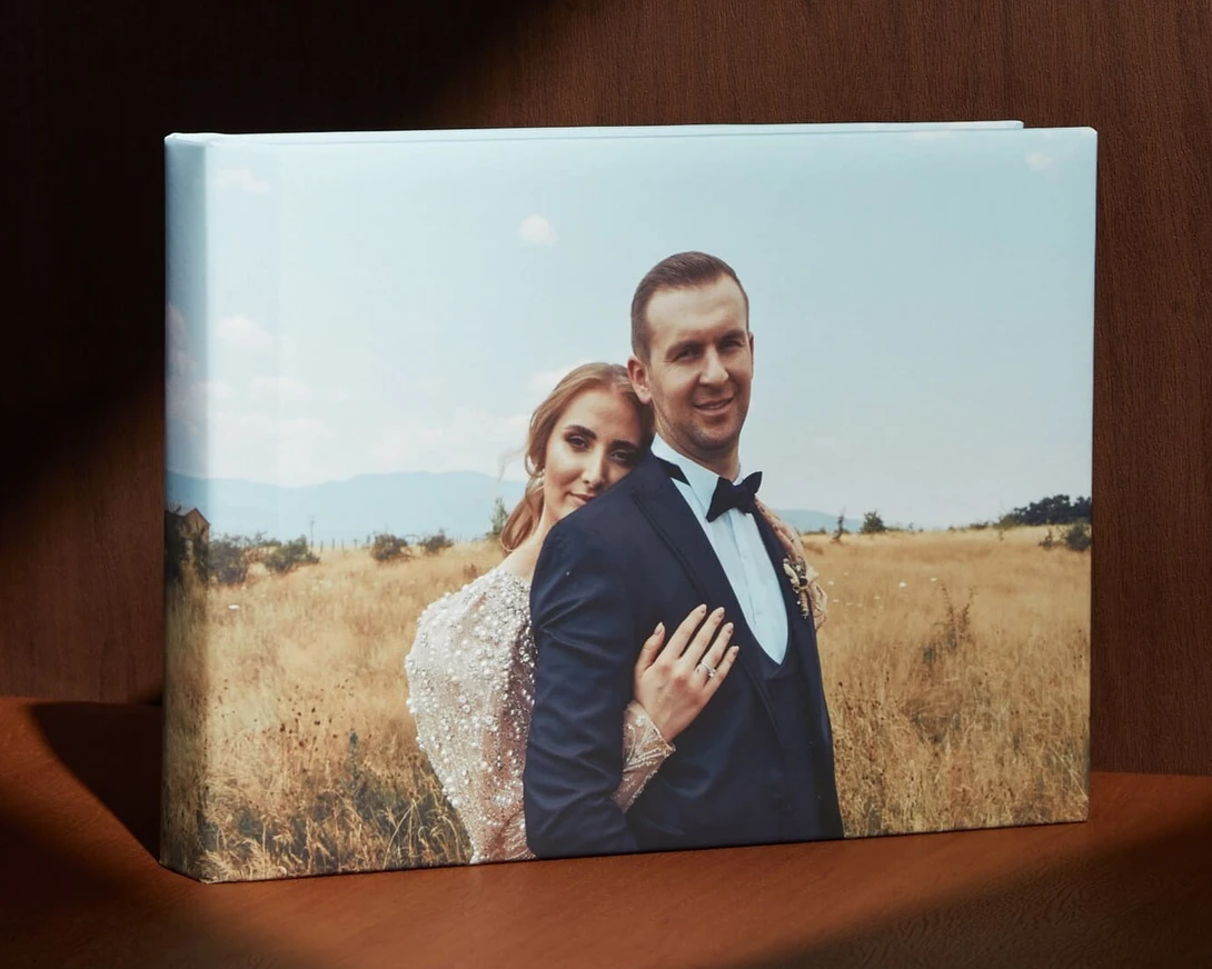 Bride and groom posed together in a golden field under clear sky.