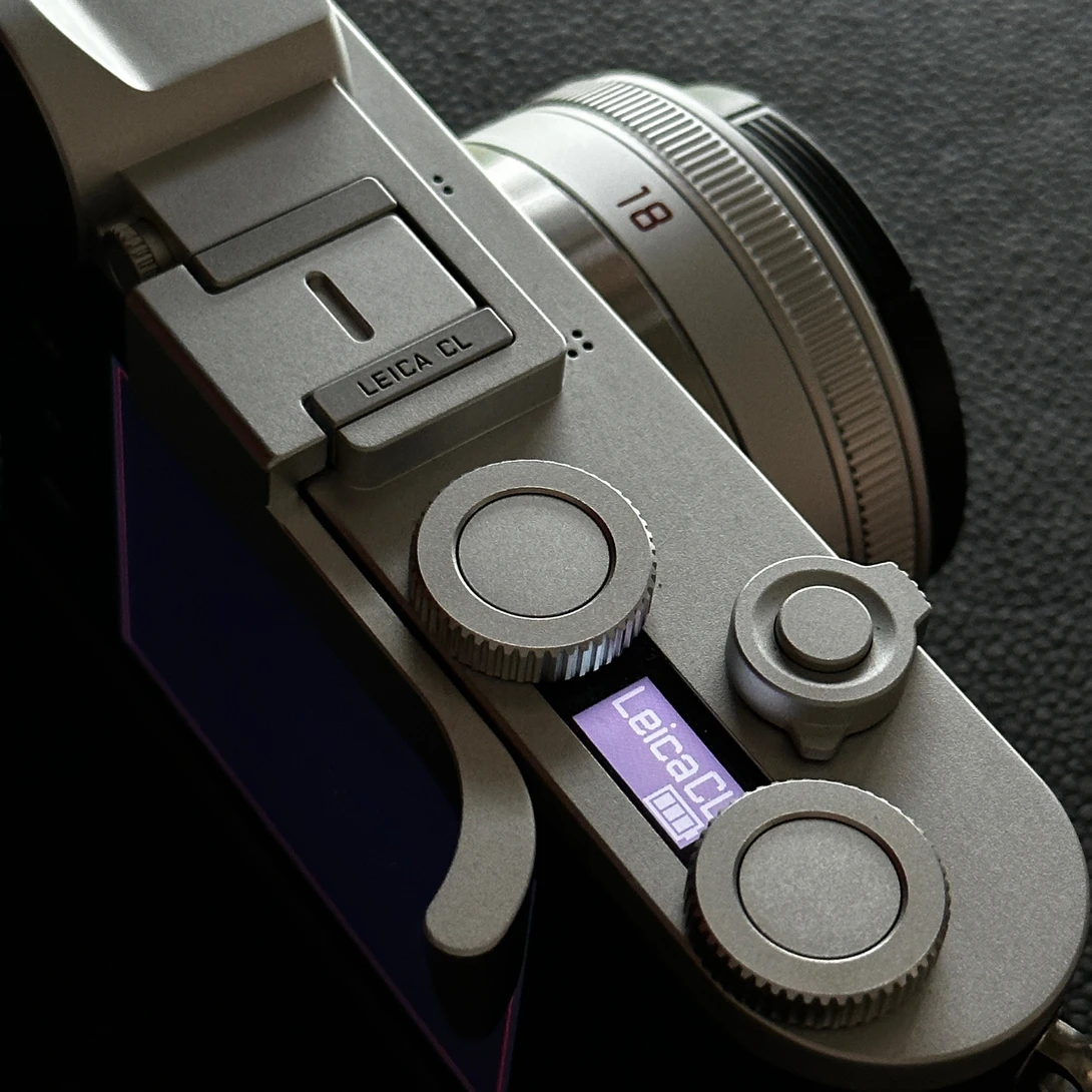 Top-down view of a silver rangefinder camera with attached lens and visible control dials.