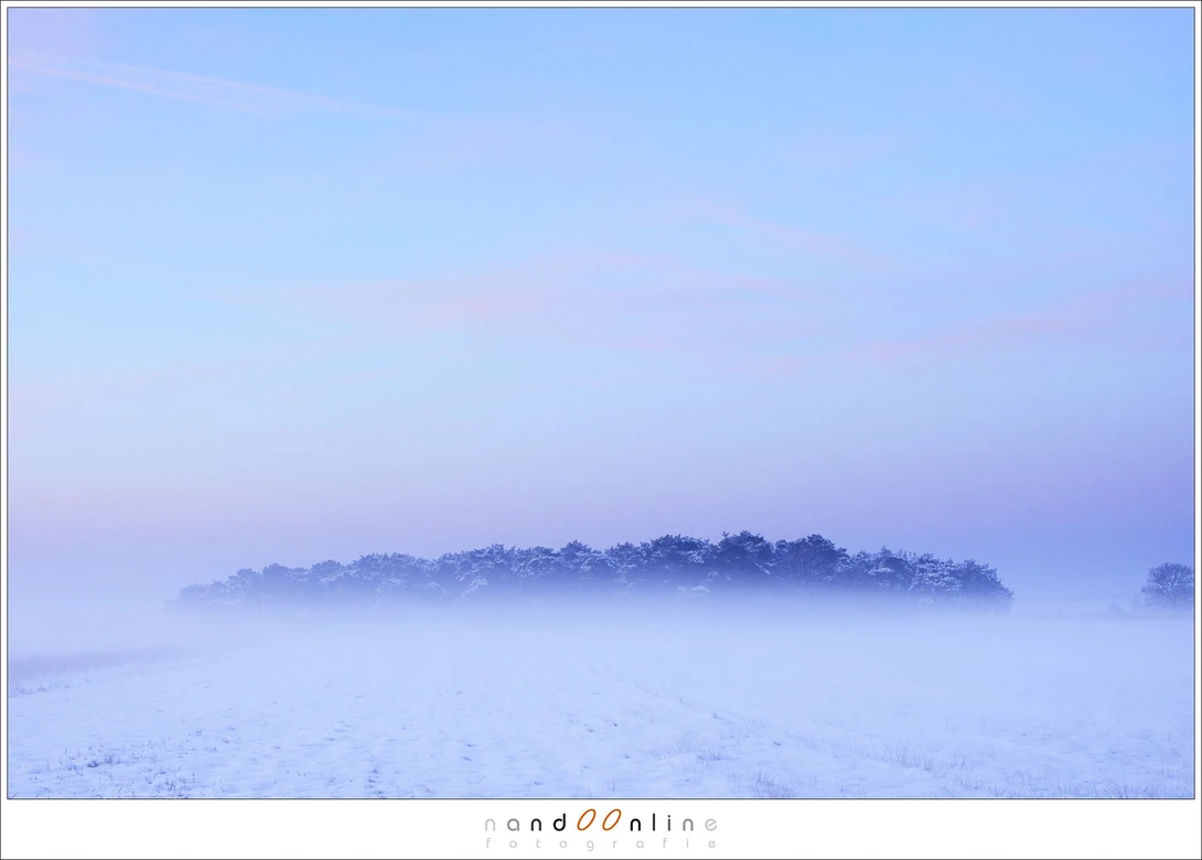 A bit of morning fog over a snow covered landscape