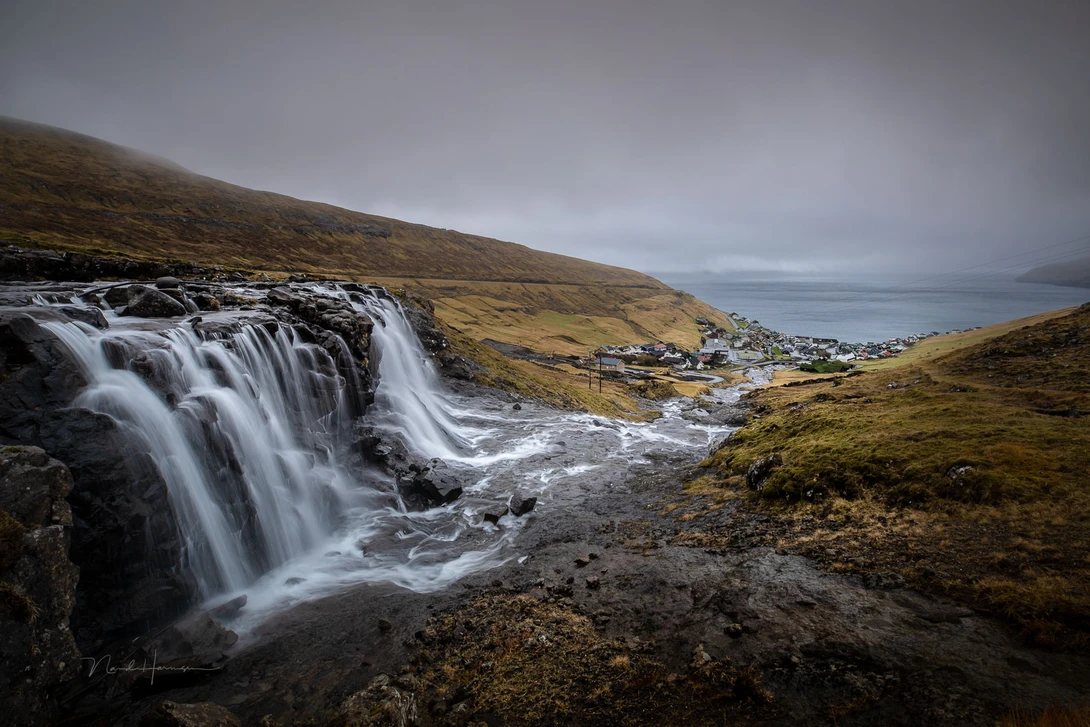 The water flows into the frame towards the small village at the horizon.