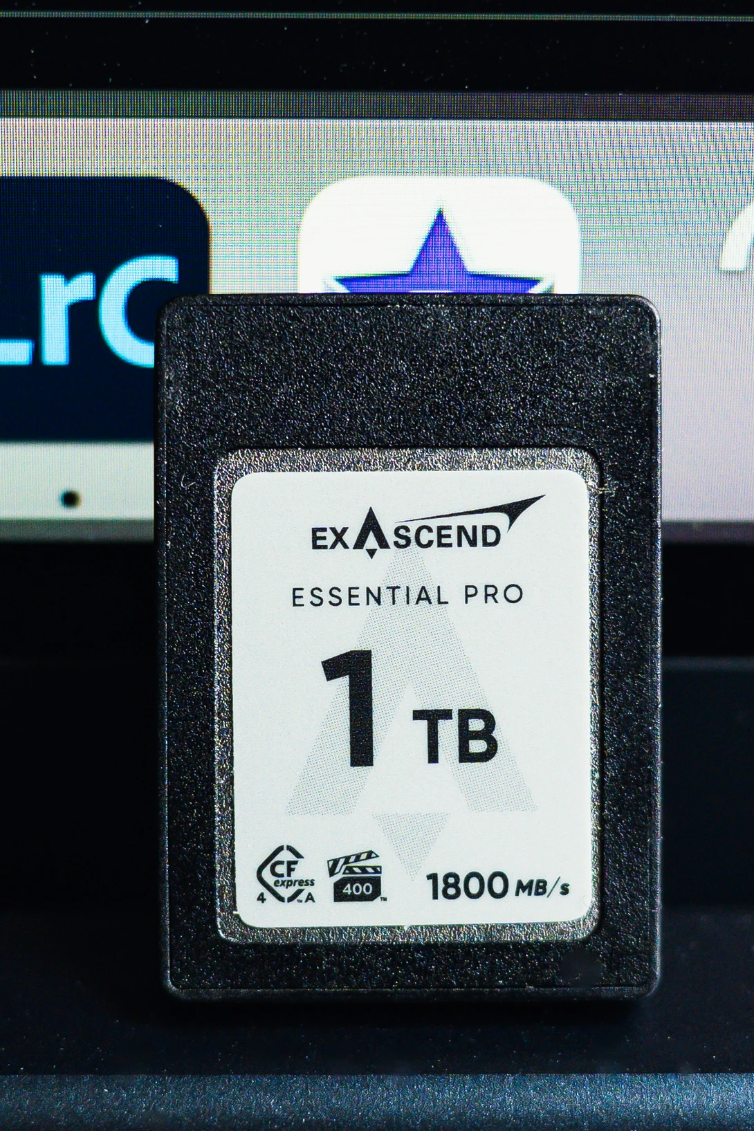 Exascend Essential Pro 1TB CFast card displayed against a laptop and desktop computer setup.