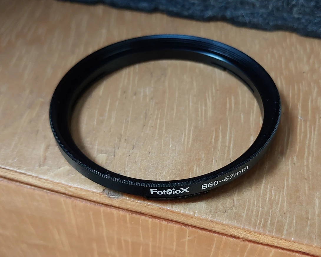 Fotobox brand lens filter with 58-57mm step-down ring, black aluminum frame.