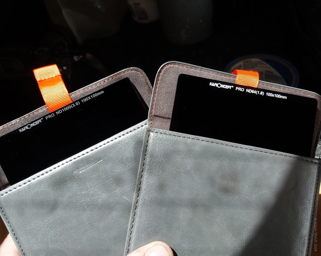 Two smartphone displays mounted in a gray protective case with orange fastening straps.
