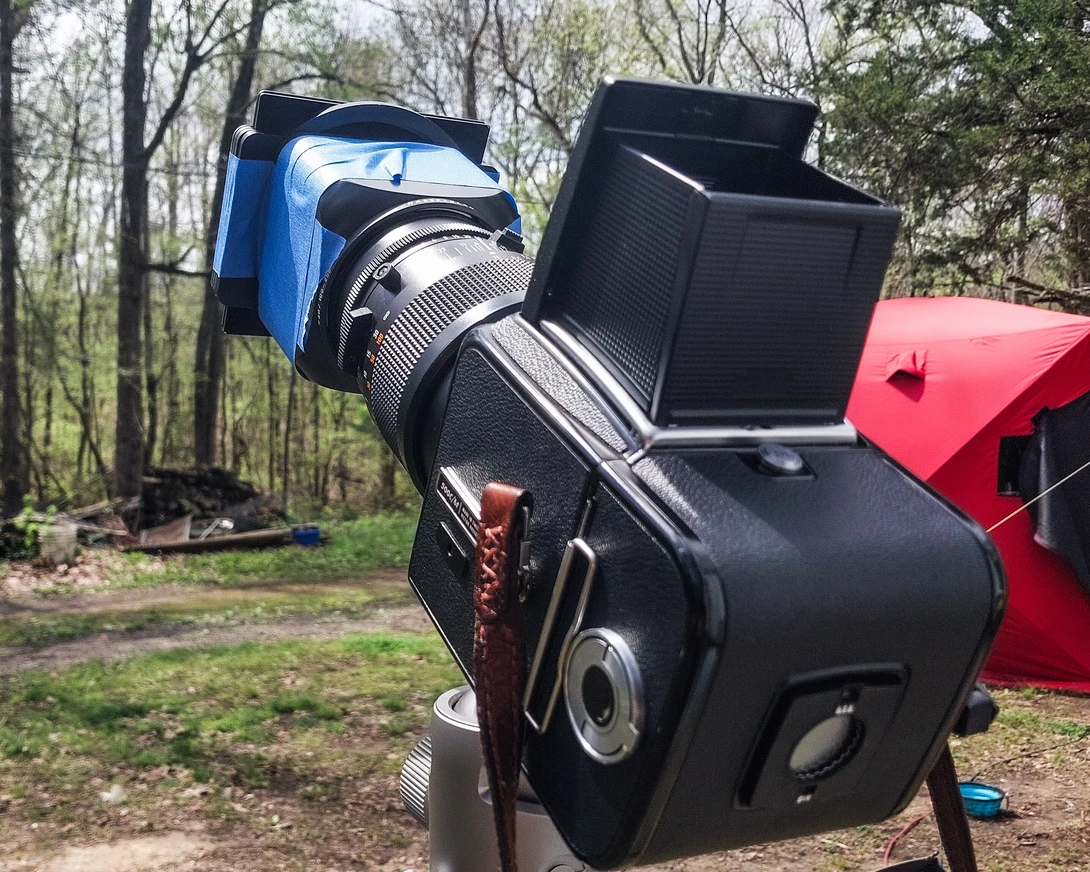 360-degree camera rig mounted on camera tripod with solar panel and various imaging equipment in outdoor wooded setting.