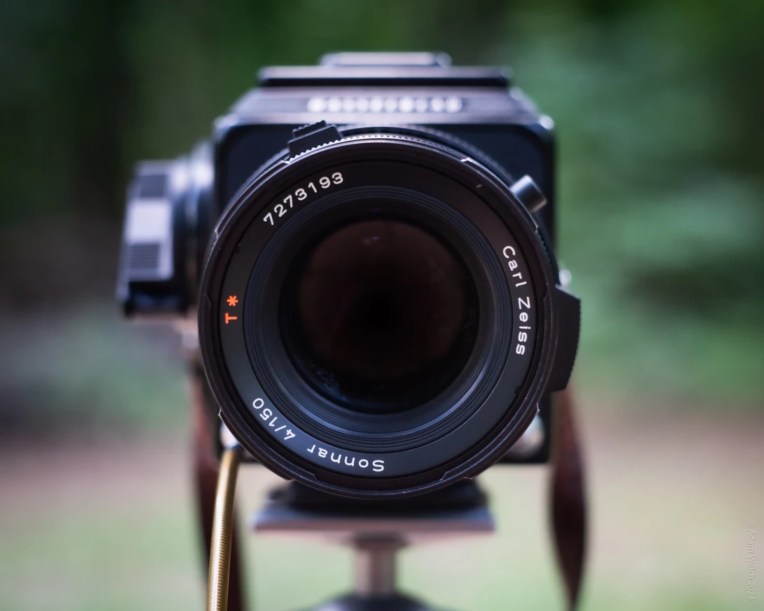 Fast prime lens mounted on medium format camera body, shot head-on with shallow depth of field background.