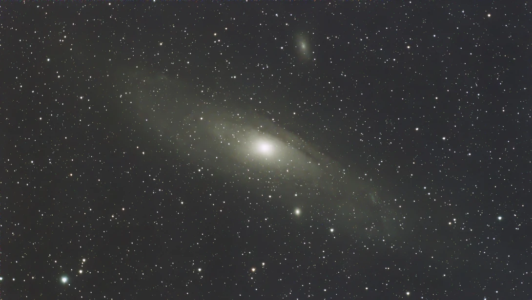 Bright elliptical galaxy with surrounding stars against dark night sky.