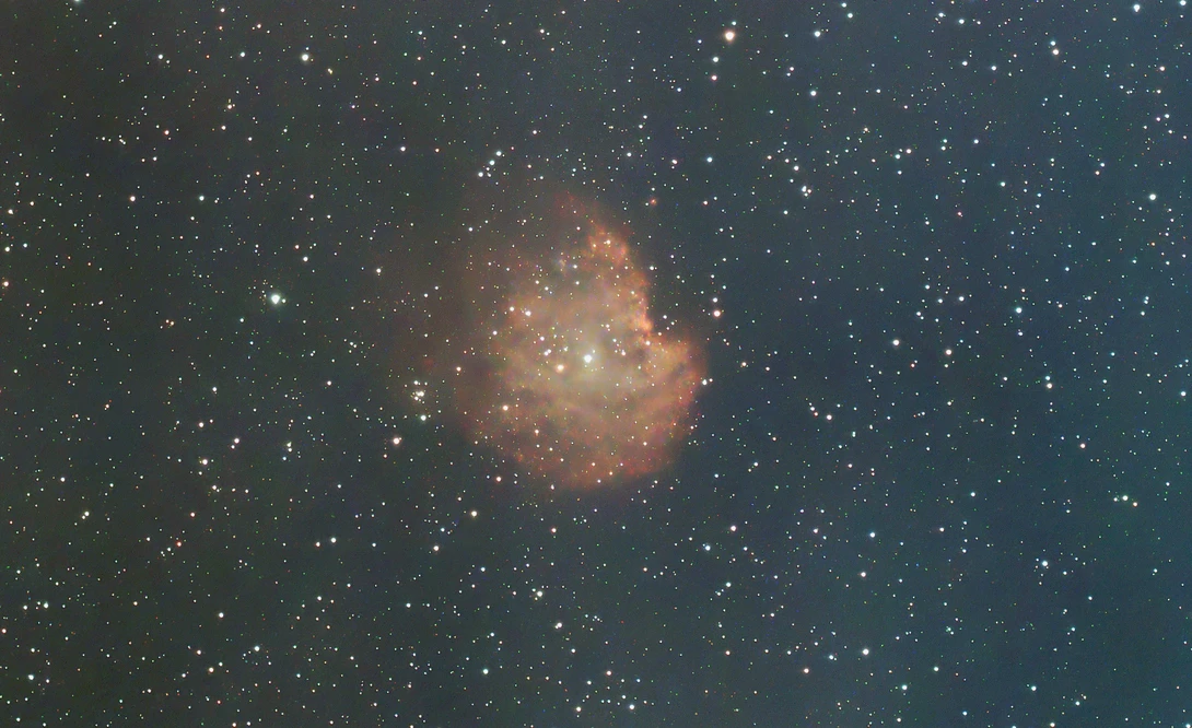 Emission nebula with golden-orange gas clouds surrounded by stars against a dark blue-black sky.