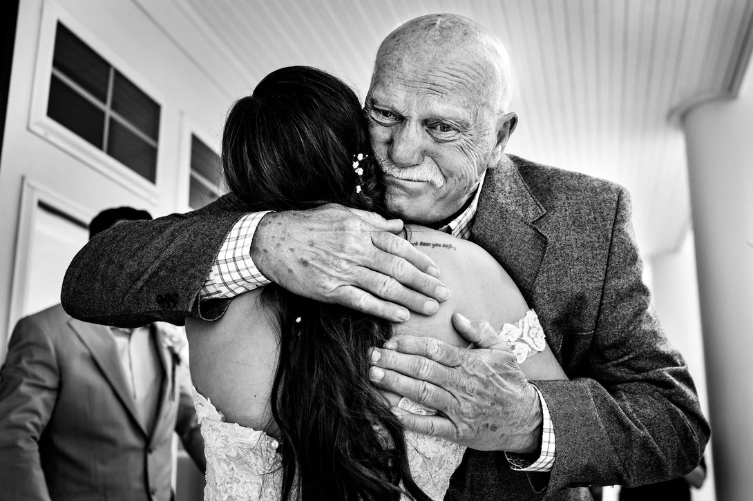 wedding photojournalism technique used for grandpa hugging the bride
