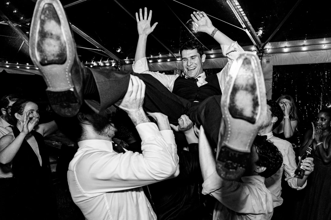 Groom is held above shoulders during wedding reception dance