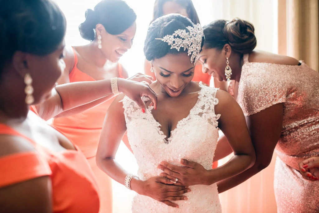 bridal party and mother help bride get dressed during bridal prep