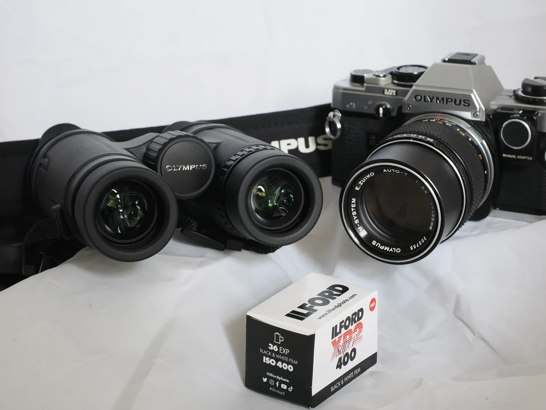 Vintage Olympus film camera bodies and lenses arranged with an Kodak film box.