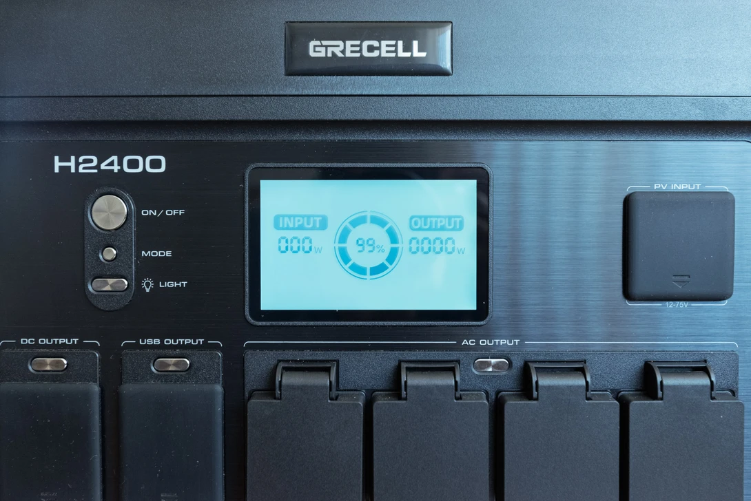 Grecell H2400 portable power station with LCD display showing input and output readings.