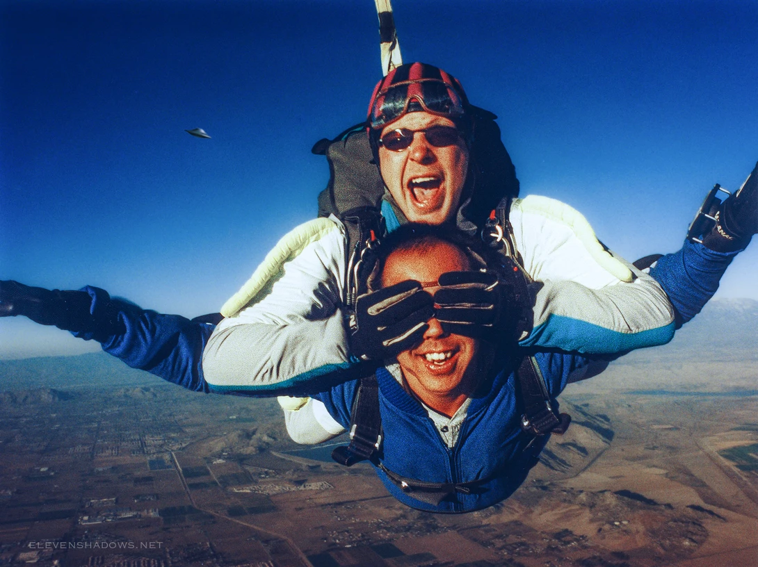 Skydiving while someone is covering my eyes, with a UFO nearby.