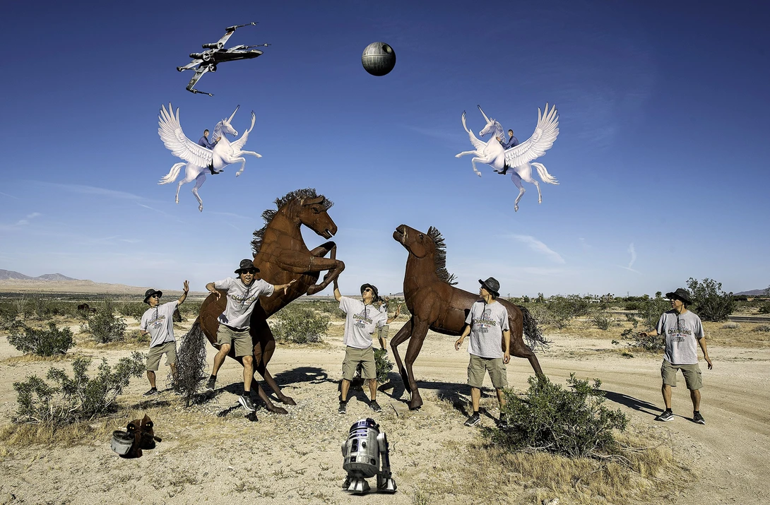 Surreal composite showing two rearing horses and people in a desert landscape with flying white birds, a helicopter, and a sphere in the sky.