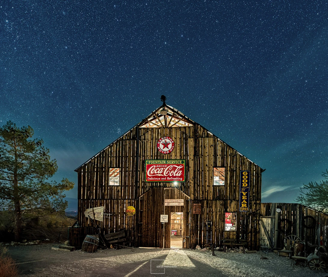 Abandoned wooden structure with vintage Coca-Cola signage against starry night sky.