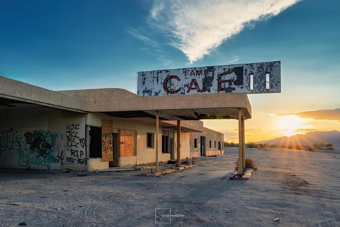 Abandoned desert motel at sunset with faded signage and weathered concrete structure.