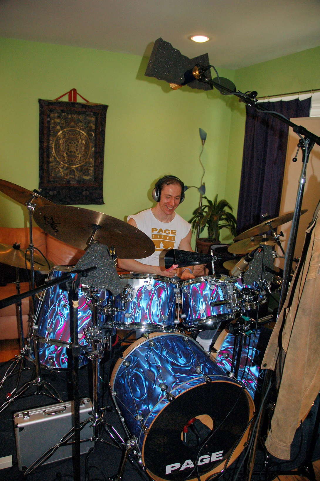 Drummer performing on a blue sparkle drum kit in a home studio with lime green walls.