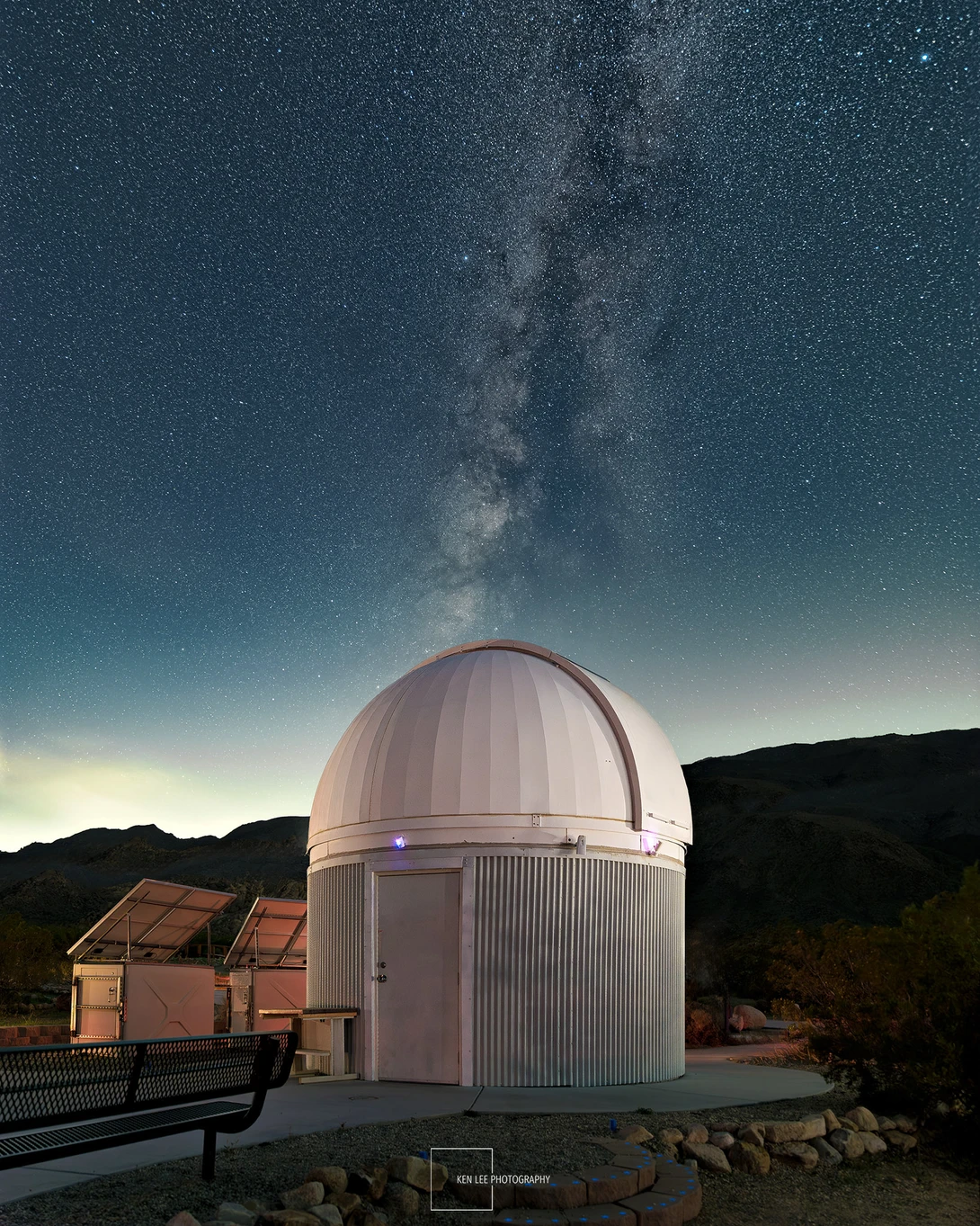 White observatory dome silhouetted against the Milky Way galaxy stretching across a starry night sky.