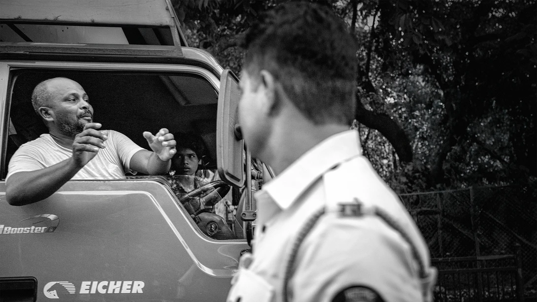 Man speaking from truck window to person in foreground, black and white street photography.