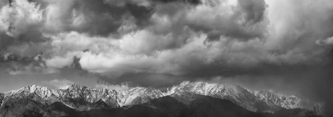 View Black and White Mountainscape with Dramatic Clouds by Roger Applegate