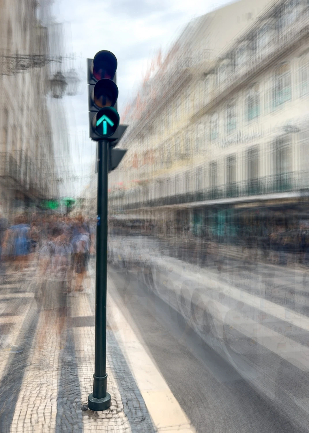 Green traffic light signal on urban street with motion-blurred vehicles and classical Parisian buildings