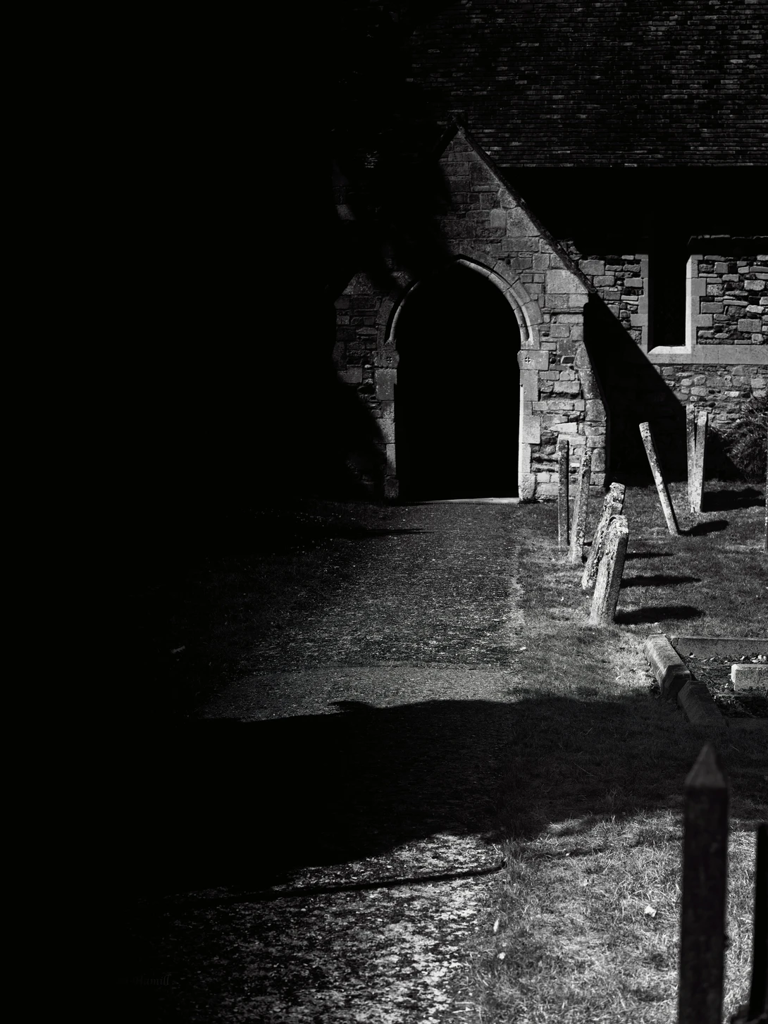 Archway entrance with dramatic high-contrast black and white lighting in a stone structure
