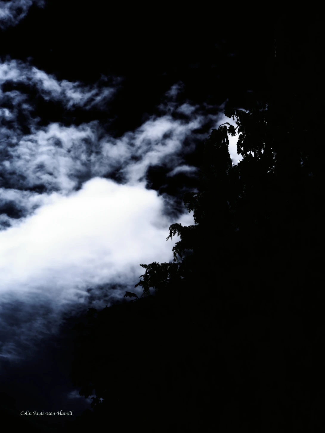 Dramatic cloud formation illuminated against dark sky with bright white light breaking through
